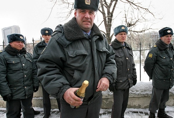 Сотрудник полиции держит в руках бутылку шампанского для главы республиканского МВД Асгата Сафарова, переданную одним из участников акции протеста против полицейского произвола у здания МВД Татарстана в Казани.