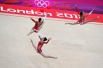 Украинские гимнастки выполняют упражнения с мячом во время квалификации в групповых соревнованиях по художественной гимнастике на ХХХ летних Олимпийских играх 2012 года в Лондоне.