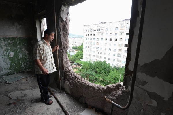 2013 г.
Мужчина, живущий в девятиэтажном аварийном доме на улице Октябрьская в городе Цхинвал, смотрит через отверстие от танкового снаряда попавшего во время войны в соседнюю квартиру.