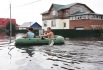 Жители поселка плывут на резиновой лодке по подтопленной улице в поселке Владимировка Благовещенского района.