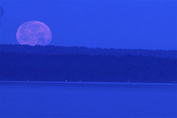 Луна во время заката над озером.