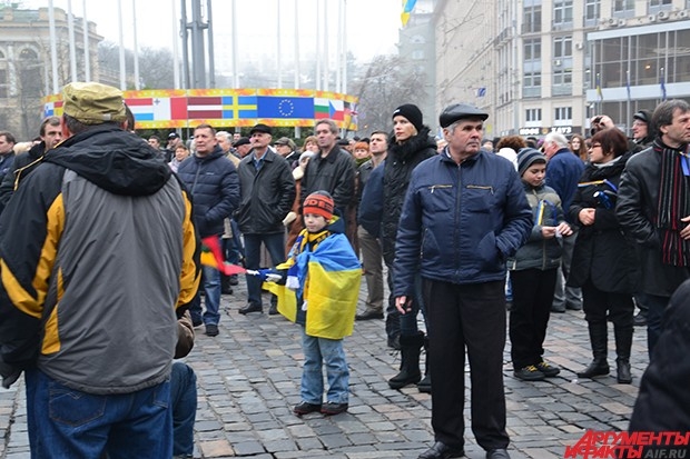 Протестующие на Майдане смотрят на приближающиеся колонны. На центральной площади уже появились ярмарочные палатки и основа для новогодней елки