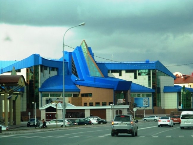 Третье место по праву занимает Музей геологии, нефти и газа. Как и большинство зданий Ханты-Мансийска оно выполнено из синего и голубого стекла. Что, впрочем, абсолютно не нарушает, а только подчеркивает гармонию с окружающей средой. Автором первого проек