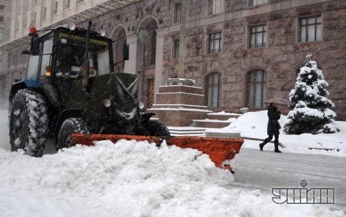 Трактор чистит дорогу во время снегопада в Киеве