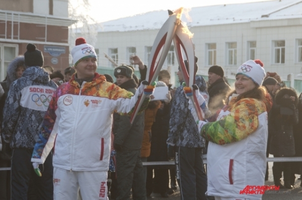 Факелоносцы бережно передают Олимпийский огонь из рук в руки.