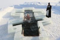 Мужчина купается в проруби, вырезанной в форме православного креста, в праздник Крещения Господня на озере Вяча под Минском.