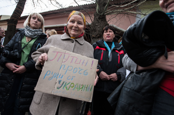 Проукраинская активистка держит плакат с надписью «Путин, руки прочь от Украины!»