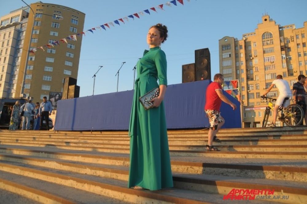 Достаточно строгое и лаконичное платье (жаль, что нет возможности рассмотреть детали), дополнено ярким клатчем. Гармоничная цветовая гамма, продуманный образ. Девушка выглядит отлично. В каждом образе, должен быть один акцент (элемент привлекающий к себе большее внимание). Здесь клатч стал тем самым акцентом.