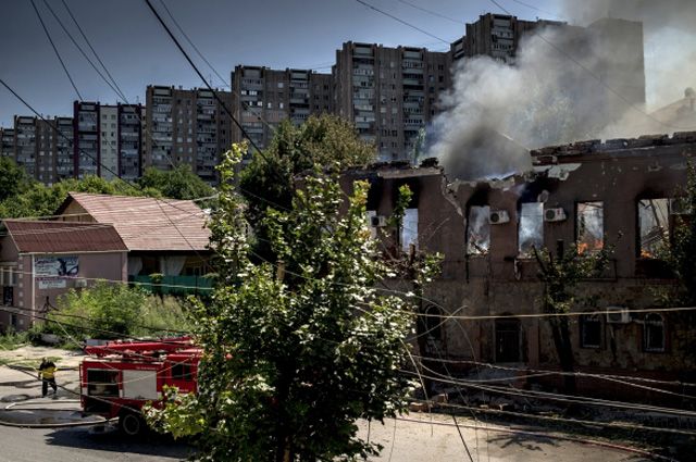 Пожар в здании, загоревшемся в результате попадания снаряда во время артиллерийского обстрела Луганска украинскими силовиками.
