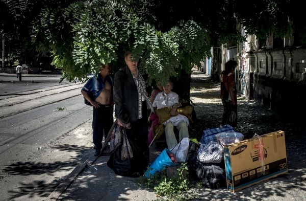 Местные жители Луганска сидят возле своего дома, разрушенного в ходе боев.
