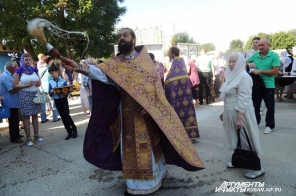 Отец Василий окропляет прихожан святой водой.