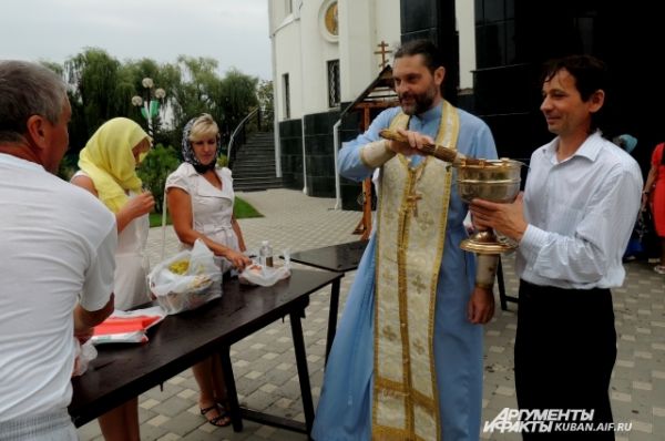 Отец Борис окропляет яблоки.