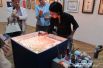 Краснодарская ученица Гарипа Ай Рената Нисимова демонстрирует посетителям выставки, как создается живопись на воде.