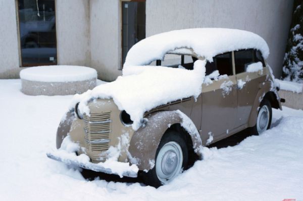 Снег ложится белым покрывалом на крыши домов, дороги и автомобили.