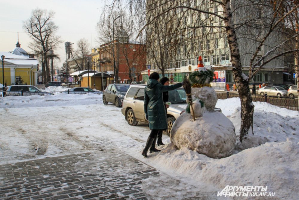 Горожане с удовольствием разглядывают снеговиков и фотографируют.