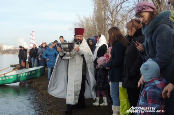 Отец Василий несет кубок с речной водой.