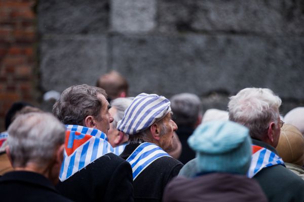 Некоторые бывшие заключенные на церемонии были одеты в характерные шапочки и робы в бело-синюю полоску, напоминающие о лагере, у других на шеи были повязаны полосатые платки.