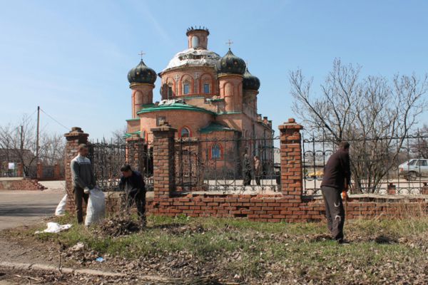 Горожане во время уборки территории храма святителя Игнатия Брянчанинова, пострадавшего в результате боевых действий в аэропорту Донецка.