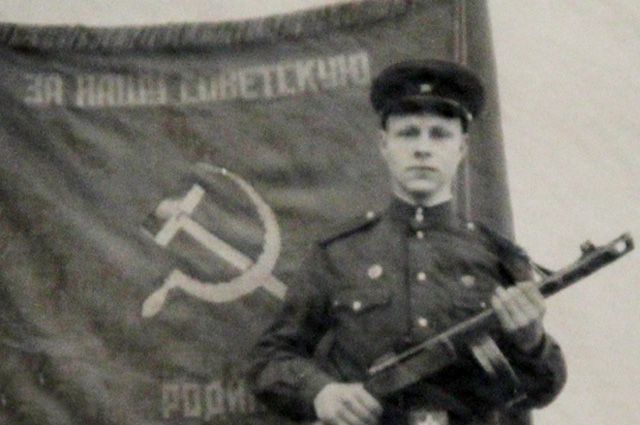 Сержант Олег Анохин на фоне знамени полка.