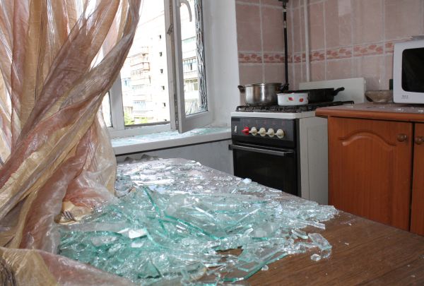 Осколки выбитых оконных стекол в квартире жилого многоквартирного дома, пострадавшего в результате обстрела города Горловки Донецкой области.