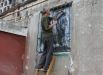 Житель Горловки закрывает окно полиэтиленовой пленкой в жилом многоквартирном доме, пострадавшем в результате обстрела города Горловки Донецкой области.