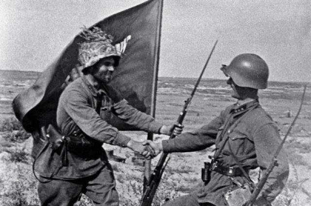 Бойцы поздравляют друг друга с победой у знамени, водружённого в окрестностях озера Хасан.