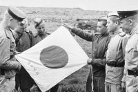 Советские воины рассматривают брошенный при отступлении японский флаг.