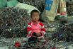 Маленький ребенок, сидящий на кабелях и электронном мусоре в Китае. Огромное количество электронного мусора регулярно (и часто нелегально) грузится на корабли, которые везут его из Европы, США и Японии в страны Азии. Гринпис призывает производителей полностью исключить токсичные материалы из своих продуктов.