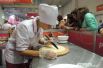 Студентка краснодарского торгово-экономического колледжа готовит пиццу под пристальным вниманием посетителей форума. 