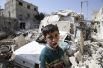 Мальчик на фоне разрушенных зданий в городе Дума, Дамаск.