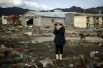 Женщина возле своего дома, разрушенного в результате землетрясения и цунами, в городе Кесеннума, 28 марта 2011 года.