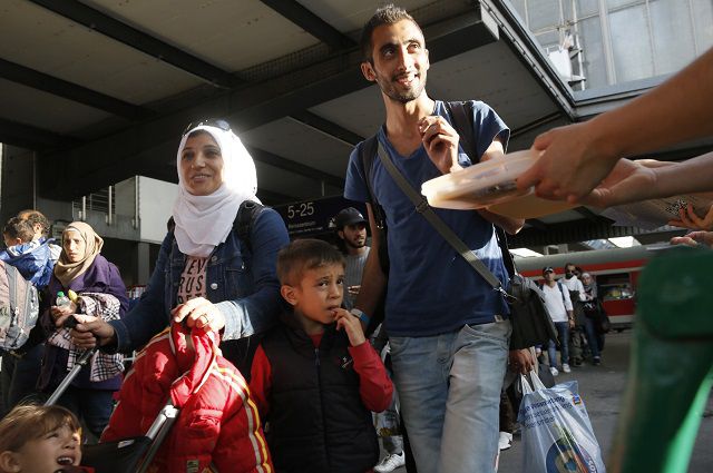 Местные жители Мюнхена раздают еду прибывшим беженцам из Сирии на центральном железнодорожном вокзале в Мюнхене.