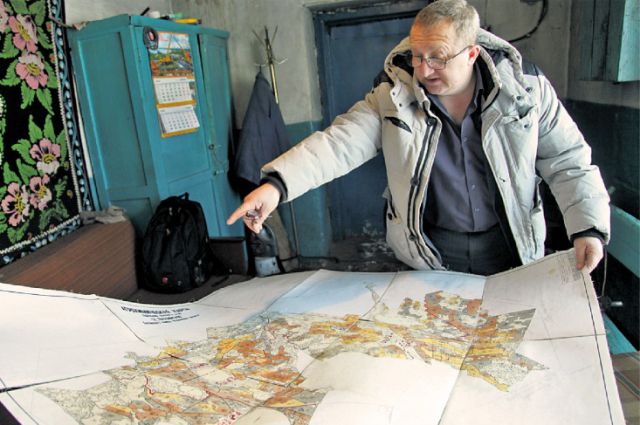 Фермер Николай Попов показывает на старой карте поля, которые сейчас заброшены.