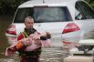 Спасатель выносит ребёнка на руках из затопленного района.