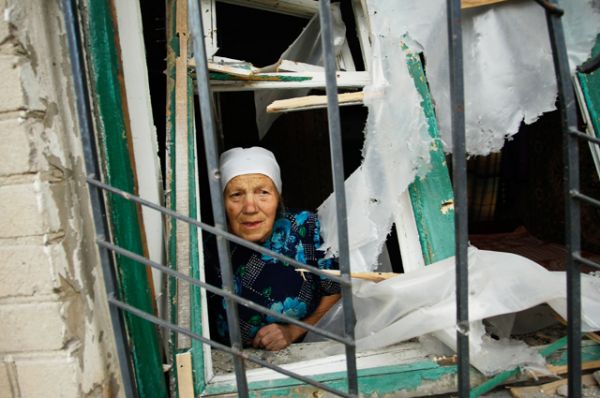 Пенсионерка в окне разрушенного дома.