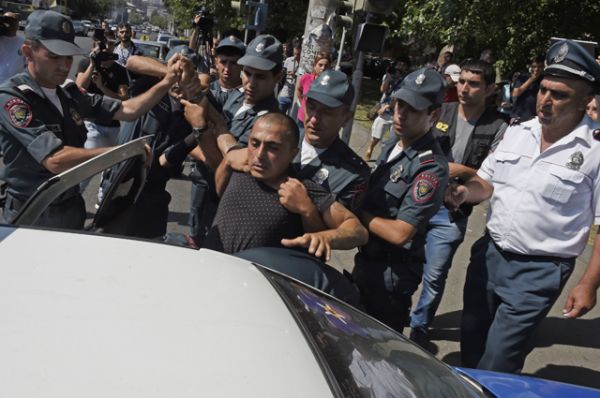 Полицейские сажают в машину задержанного у захваченного здания отделения полиции в районе Эребуни на окраине Еревана. 