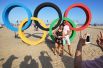 Отдыхающие фотографируются у олимпийских колец на пляже Копакабана в Рио-де-Жанейро.