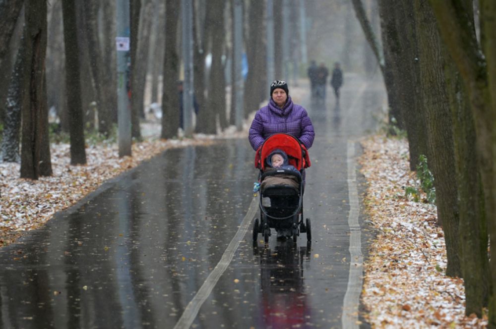 Прохожие на аллее в Москве, где выпал первый снег.