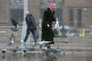 Женщина кормит голубей на улице в Москве, где выпал первый снег.