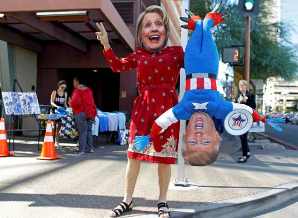 Человек в костюме Хиллари Клинтон с куклой Дональда Трампа в руках. 