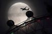 Колесо обозрения London Eye на фоне восходящей Луны в Лондоне.