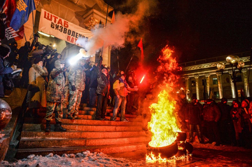 Участники акции, посвященной годовщине начала событий на Майдане, жгут файеры и автомобильные покрышки в Киеве.