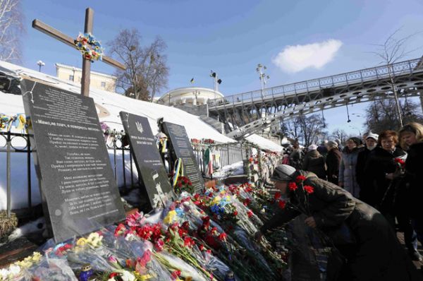 Люди возлагают цветы к мемориалу в память об убитых в ходе столкновений.