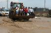Экскаватор перевозит жителей после массивного оползня и наводнения в районе Уачипа в Лиме.