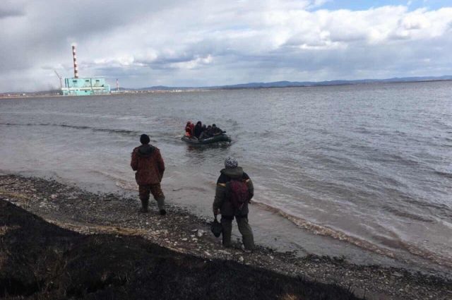 Спасатели снимают людей с льдины, полицейские принимают их на берегу.
