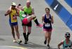 Бегуны Уолтер Данбар и Мэдисон Смит помогают участнице Бибо Гао, которой стало плохо в время забега, пересечь финишную линию 121-го Бостонского марафона.