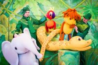Ведомые кукольными персонажами спектакля «38 попугаев», участники представления весело прошествуют из первой очереди торгового центра во вторую.