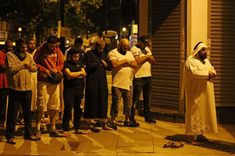 Мужчины молятся возле места происшествия в Лондоне.