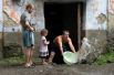 Мужчина вычерпывает воду из подъезда на затопленной улице Уссурийска. 