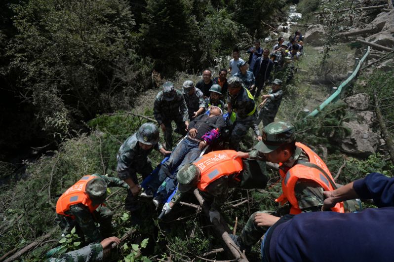 Китайские спасатели несут пострадавшего после землетрясения в округе Цзючжайгоу.